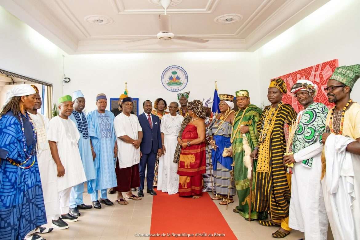 Dominique Brutus, chargée d'affaires a.i. de l'ambassade d'Haïti au Bénin, entourée de dignitaires diplomatiques et d'autorités royales béninoises en tenues traditionnelles, lors de la cérémonie officielle de réouverture de l'ambassade à Cotonou, le 18 mai 2026. © Ambassade de la République d'Haïti au Bénin / Presslakay